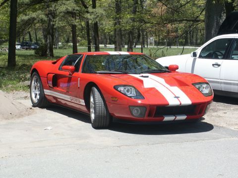 2001 Mercury Grand Marquis - A red Ford GT sports car with white racing stripes is parked next to a white SUV. The car's "GT" badging is visible on its side.