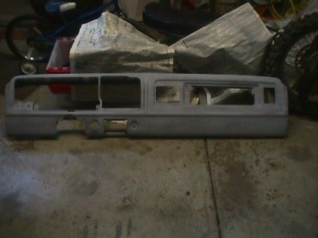 Gray dashboard assembly with multiple cutouts for gauges and controls