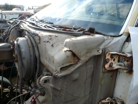 1975 Ford Ranchero - Close-up view of the rusted engine bay and firewall of a classic vehicle, showing the brake booster and various hoses and wiring. The vehic…