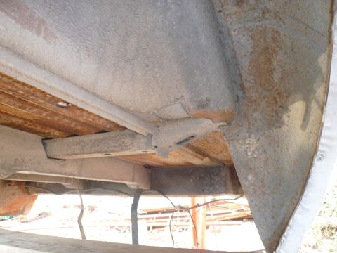1975 Ford Ranchero - The underside of a vehicle shows rusted wooden bed planks supported by metal framing and crossmembers. The metal components are heavily rus…