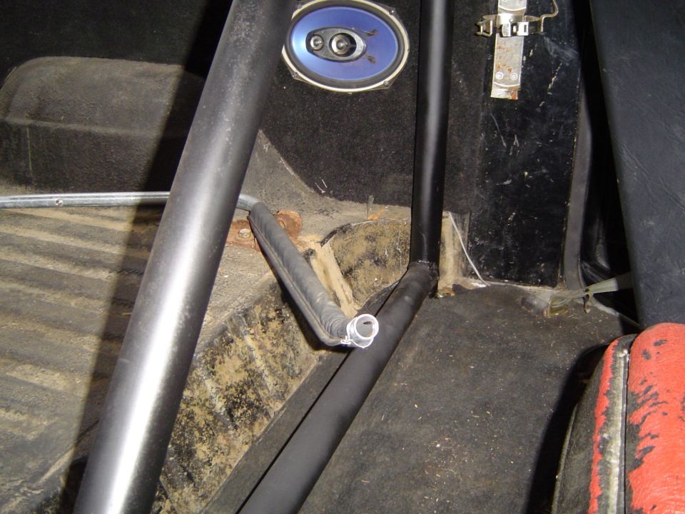 Interior of a vehicle with a black roll cage and a rubber hose.