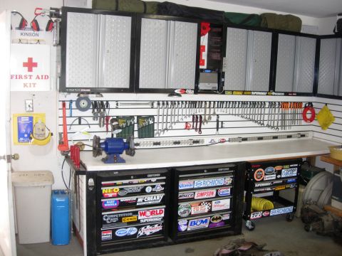 1993 Ford Bronco - A well-organized garage workbench features tool storage, a grinder, and numerous decals adorning the cabinets.