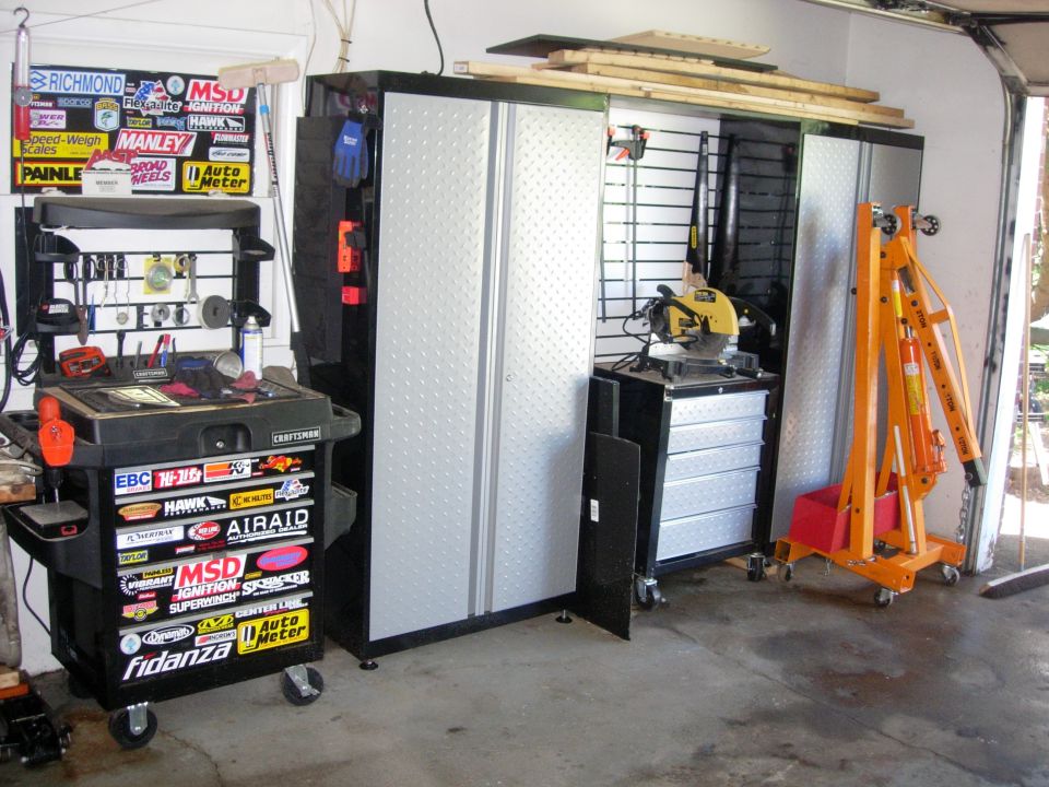 Garage interior with tool chest, storage cabinets, chop saw, and engine hoist