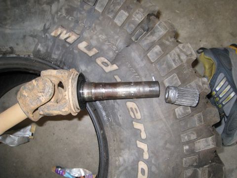 1996 Ford Bronco - A driveshaft U-joint and a splined shaft are shown disassembled next to a BFGoodrich Mud-Terrain tire.
