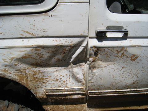1996 Ford Bronco - This 1996 Ford Bronco shows significant damage to the side door and fender, covered in mud.