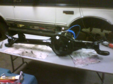 1993 Ford Bronco - A black rear axle assembly is laid out on a table, with a white SUV visible in the background.
