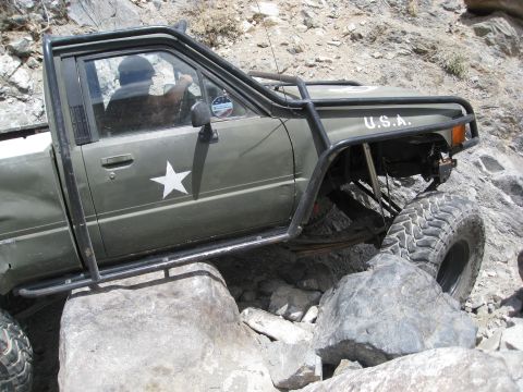 1994 Jeep YJ - This modified pickup truck navigates a rocky trail, military-style markings and a roll cage.
