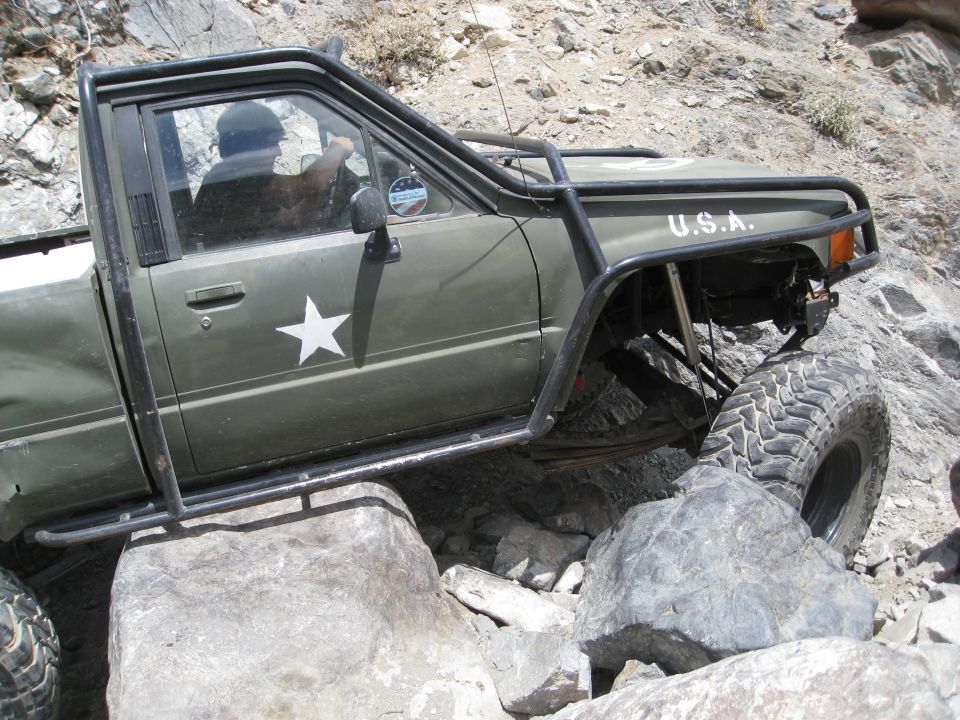 Olive green pickup truck with white star and "U.S.A." text, off-roading