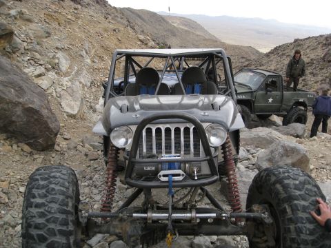 1994 Jeep YJ - Two off-road vehicles navigate a rocky trail in a desert landscape.