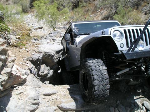 1986 Toyota Hilux - A silver Jeep Wrangler navigates a challenging rocky trail, demonstrating its off-road capabilities.