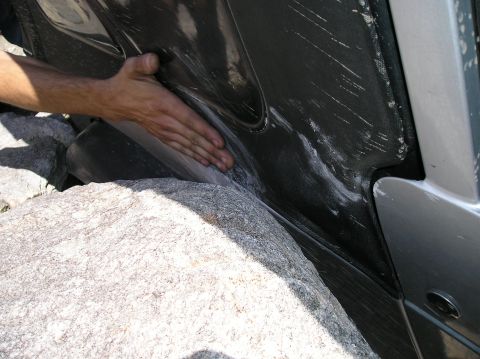 1986 Toyota Hilux - A hand is shown pressing against a vehicle's fender, which is lodged against a large rock.