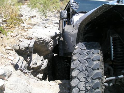 1986 Toyota Hilux - A Jeep Wrangler maneuvers through a narrow, rocky off-road path, its off-road capability.