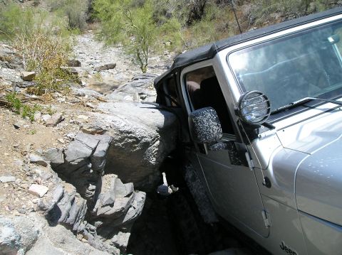 1986 Toyota Hilux - A silver Jeep Wrangler maneuvers through a challenging rocky terrain, demonstrating its off-road capabilities.
