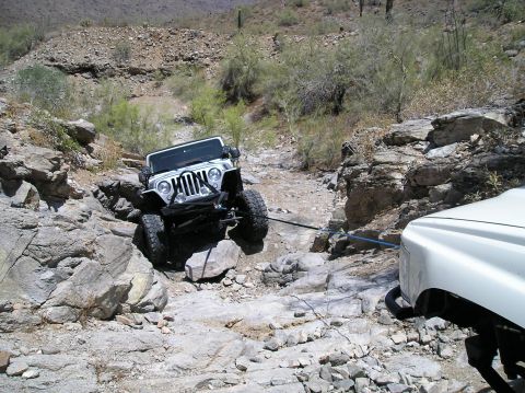 1986 Toyota Hilux - Two vehicles navigating a difficult rocky terrain in a desert environment.