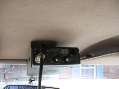 1994 Ford Bronco - A Cobra CB radio is mounted to the interior headliner of a vehicle, with a view of the outside through the windshield.
