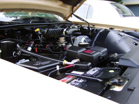 1996 Mercury Grand Marquis - The engine bay of a 1996 Mercury Grand Marquis, a supercharger and a tan exterior, with another vehicle partially visible.