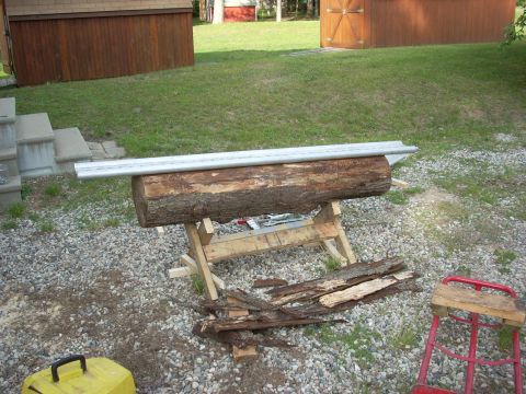 2000 Chevrolet Tahoe - A log is positioned on a sawhorse, with bark debris scattered nearby and a Supermotors logo visible in the lower right corner.