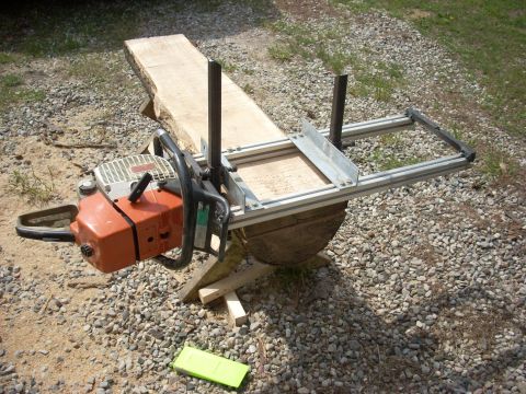 2000 Chevrolet Tahoe - A chainsaw mill attachment is set up outdoors on a gravel surface, ready to cut a wooden beam.
