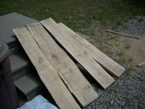 2000 Chevrolet Tahoe - Several rough-cut wooden planks are laid out on gravel and grass near a set of concrete steps.