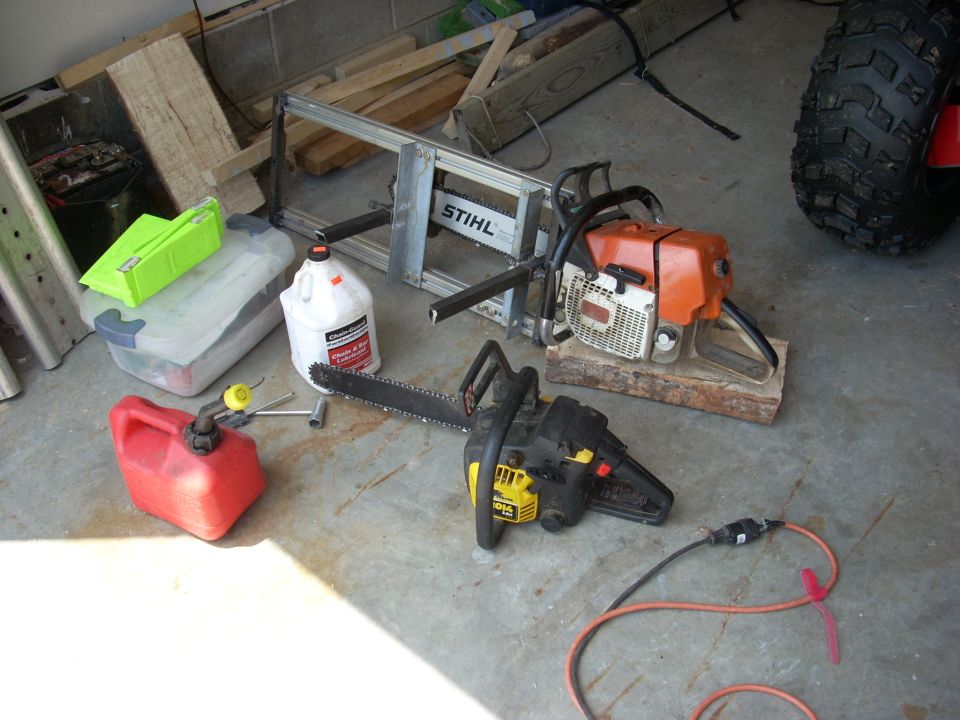 Two chainsaws, a red gas can, and a jug of oil on a concrete floor