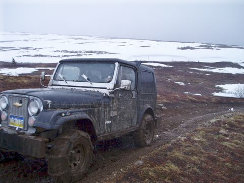 2000 Ford E350 - Jeep CJ navigating a muddy trail with snow in the distance.