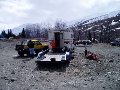 2000 Ford E350 - Several vehicles and people gathered in a rocky, mountainous area with a cloudy sky.