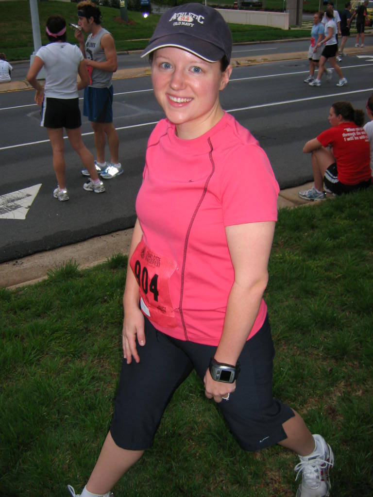 Woman in pink shirt, black capris, and baseball cap with race bib number 004