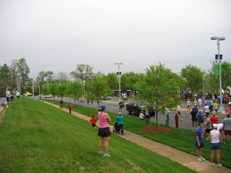 Green grass slope with people watching a marathon on a cloudy day