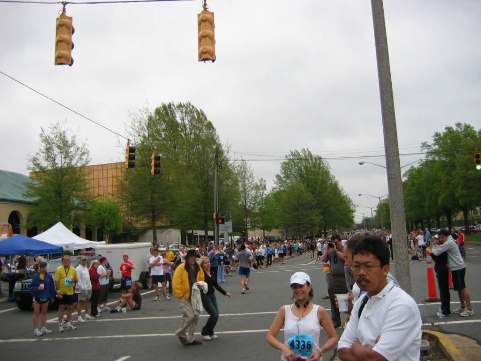 Marathon runners and spectators on a street with traffic lights and tents