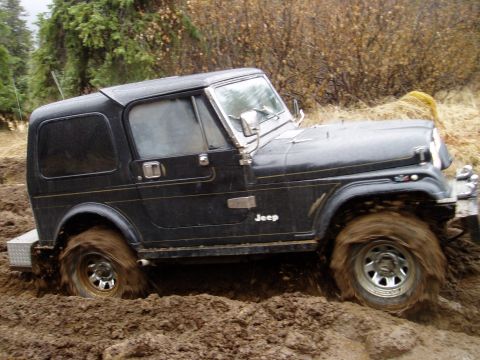 2000 Ford E350 - This Jeep is deep in the mud, with its tires churning up the dirt.