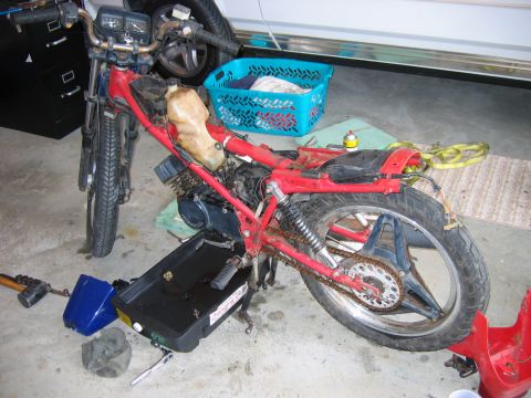 1985 Ford LTD Crown Victoria - A red motorcycle is disassembled in a garage, with parts laid out for maintenance.