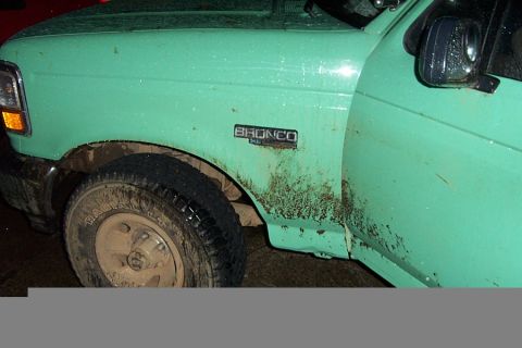 1996 Ford Bronco - Side view of a 1996 Ford Bronco, mud splattered on the fender and door.