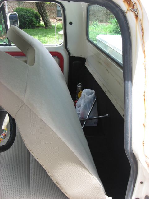 1972 Ford F-100 - The interior of a truck cab shows a seat, floor, and a window looking out to greenery. A jack and can are visible on the floor.