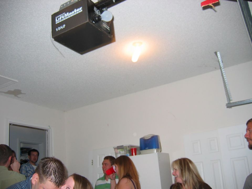 Garage interior with a LiftMaster garage door opener on the ceiling and several people gathered