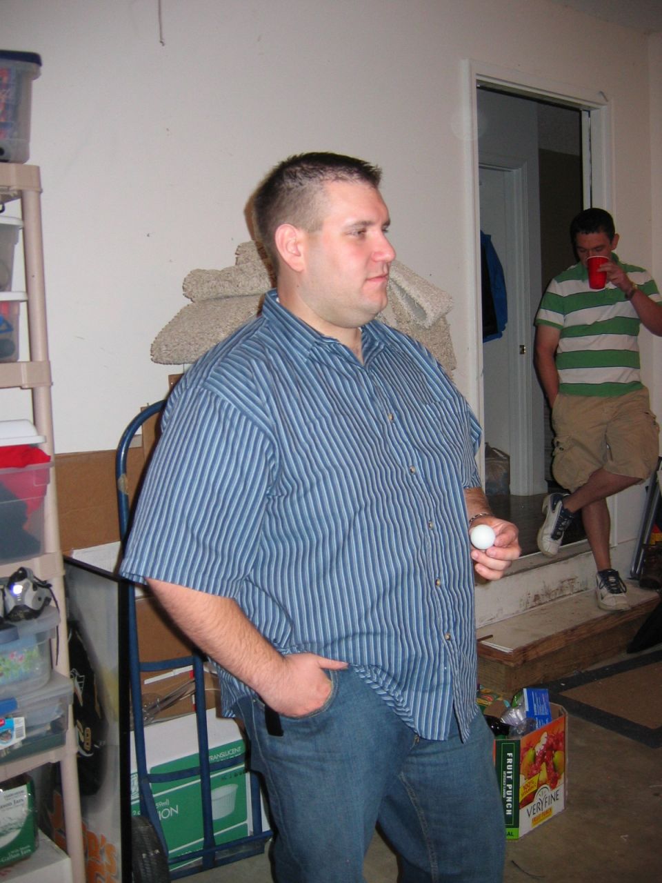 Two men in a garage, one holding a ping pong ball