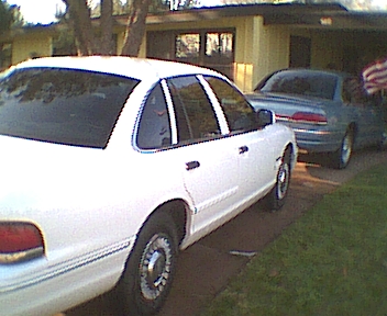 1995 Ford Crown Victoria - A white 1995 Ford Crown Victoria is parked in a driveway next to a blue sedan.