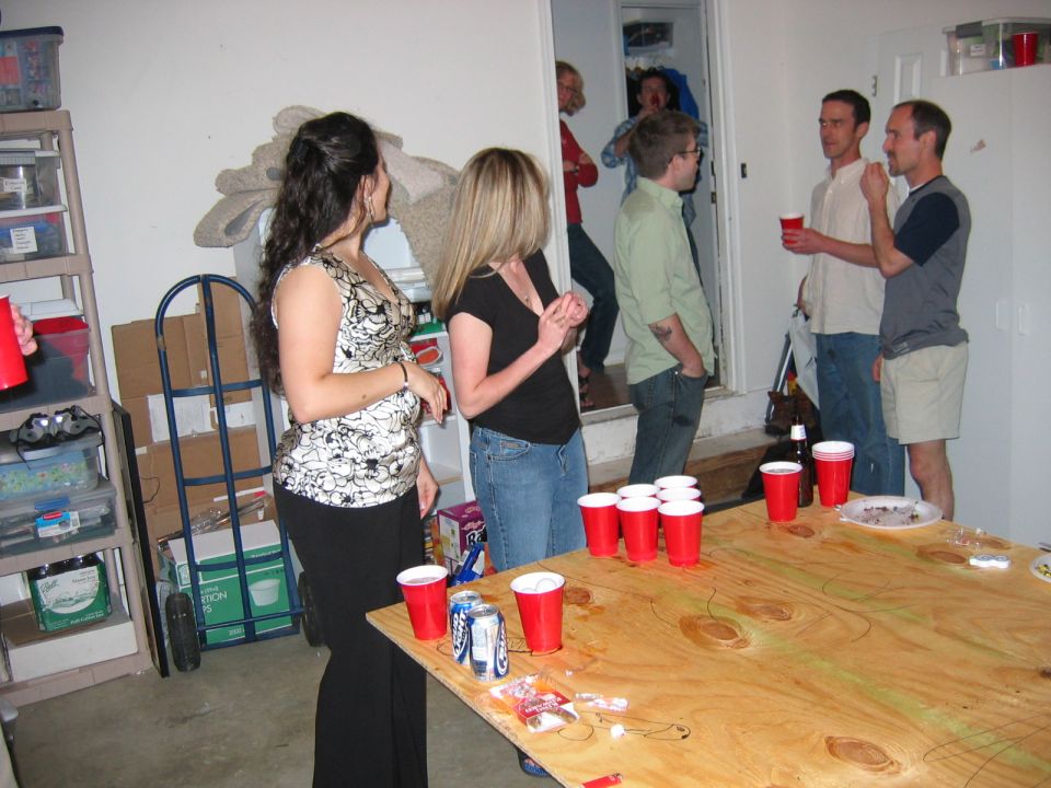 People standing around a beer-pong table in a garage