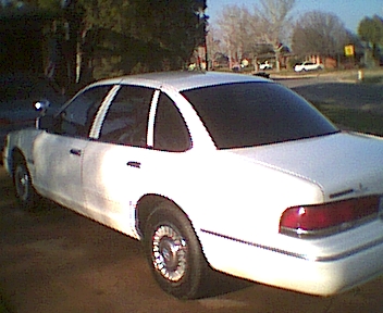 1995 Ford Crown Victoria - Side profile of a white 1995 Ford Crown Victoria sedan with tinted windows.