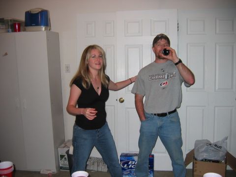 1985 Ford LTD Crown Victoria - Party photo of two people standing in a garage with beer cases on the floor, not a technical document.