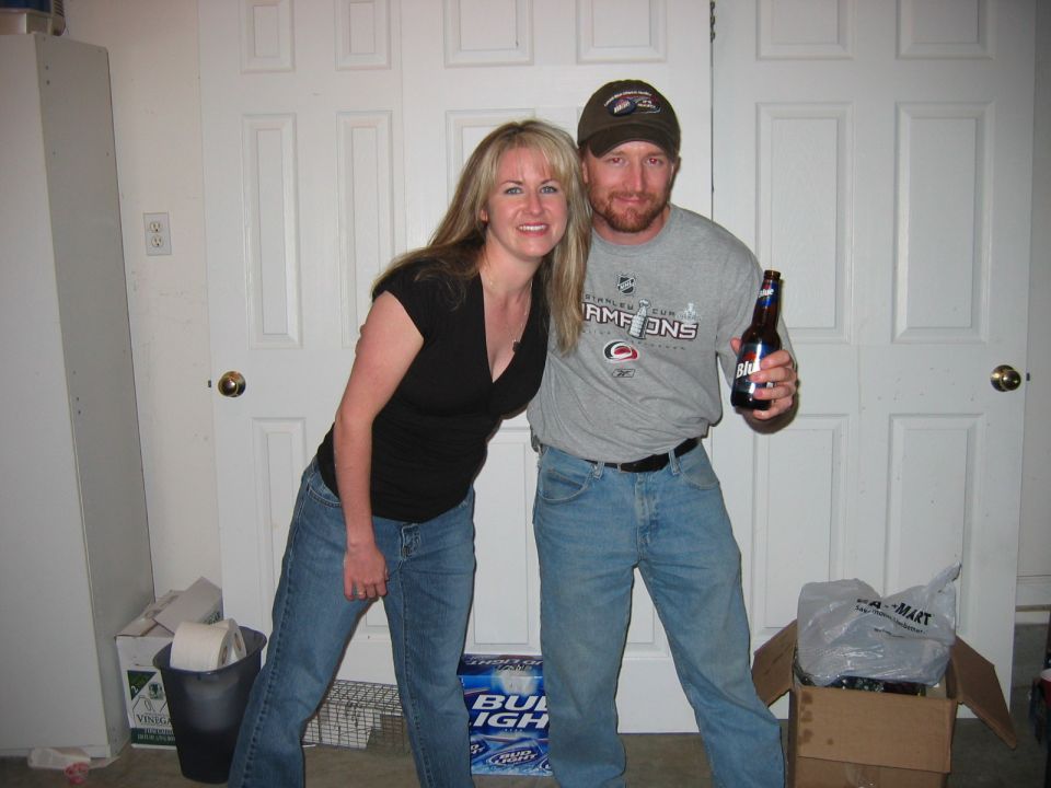 woman and a bearded man holding a beer posing in front of white doors