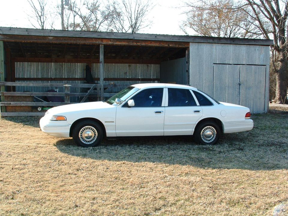 White sedan parked in front of a shed