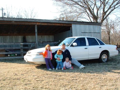 1995 Ford Crown Victoria - A family gathers for a photo in front of a white 1995 Ford Crown Victoria sedan.