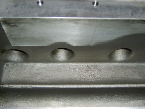 1996 Mercury Grand Marquis - Close-up of a machined aluminum casting, likely an intake manifold or cylinder head component, showing three round ports/recesses along a r…