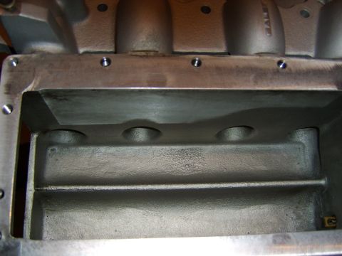 1996 Mercury Grand Marquis - Close-up looking into the valley of an aluminum engine block or intake casting, showing the machined lifter valley area with three circular…