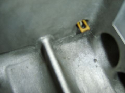 1996 Mercury Grand Marquis - Extreme close-up of a bare aluminum cast metal surface, likely an engine or transmission component, showing a machined channel and drilled…