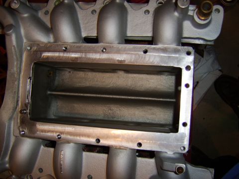 1996 Mercury Grand Marquis - Top-down view of a cast aluminum intake manifold with a large rectangular opening machined into the plenum area, revealing internal runner…