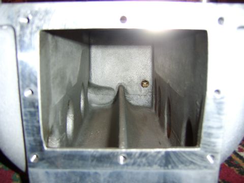 1996 Mercury Grand Marquis - Close-up looking into the plenum of a cast aluminum intake manifold, showing the internal divider walls and runner openings with a threaded…