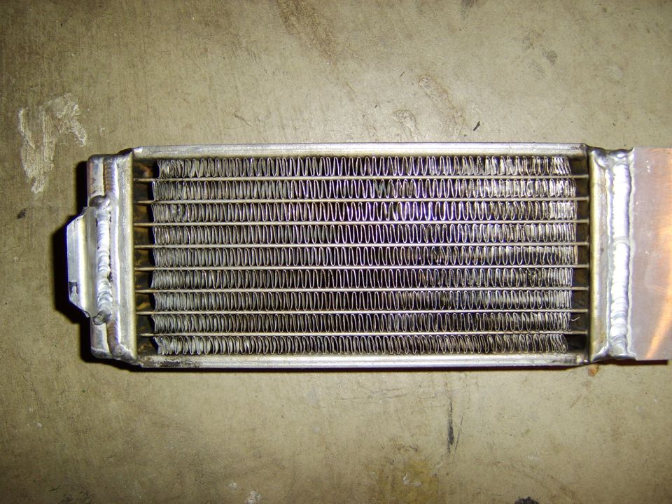 Small aluminum finned fluid cooler with welded end tanks on concrete floor