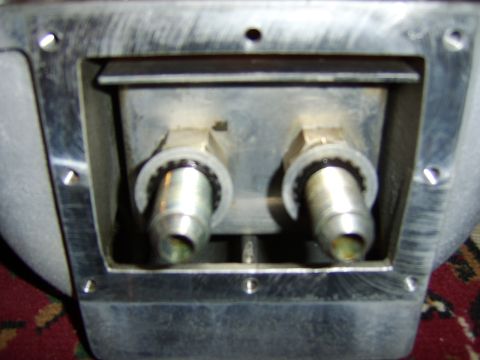 1996 Mercury Grand Marquis - Close-up of a machined aluminum bracket or housing with two threaded metal fittings protruding, secured by knurled ferrules; multiple bolt…