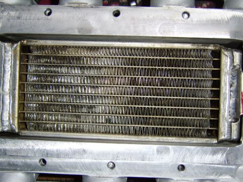 1996 Mercury Grand Marquis - Close-up of an aluminum heat exchanger or intercooler core showing rows of finned tubes framed by welded end tanks, likely part of a superc…